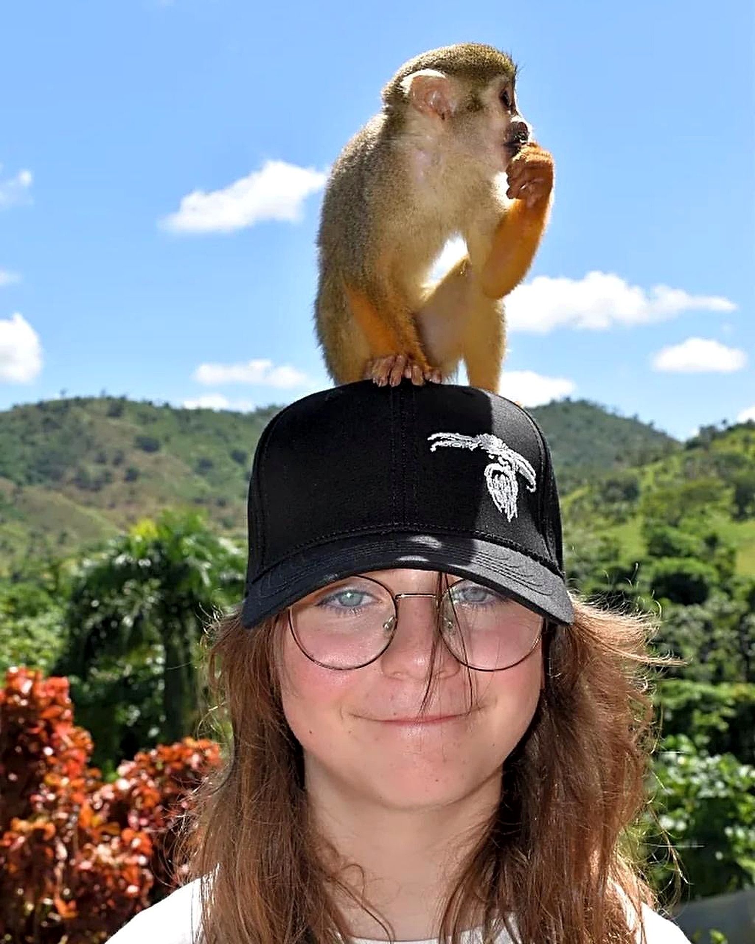 Visitor with a squirrel monkey perched on her cap at Monkeyland Punta Cana